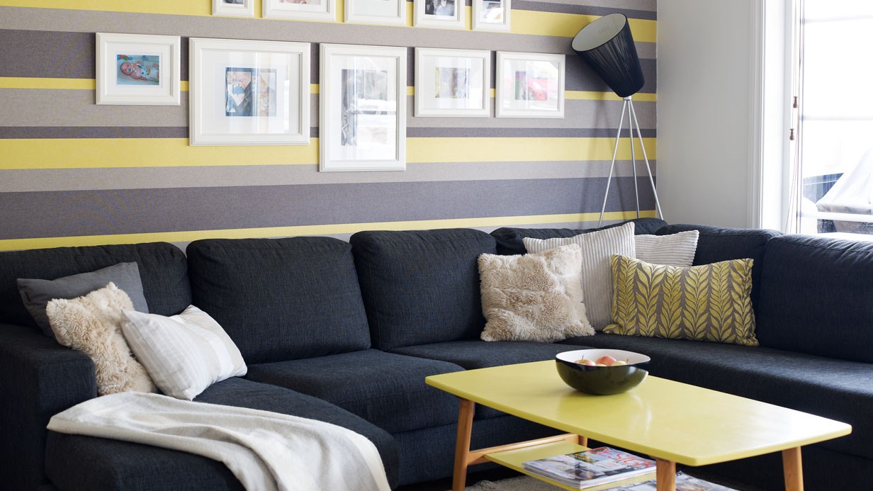 Mørk, stor sofa og lime-gult bord i stue