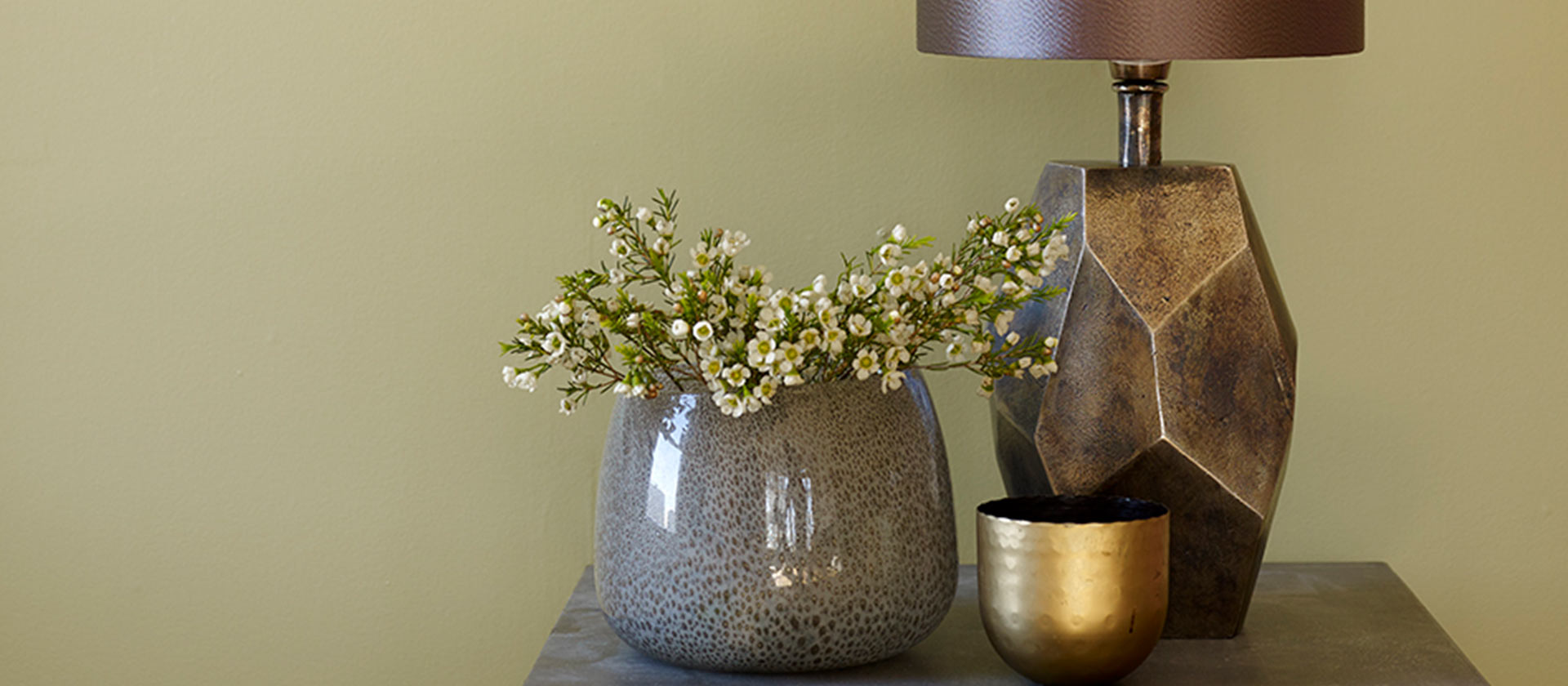 Blomstervase og lampe på bord.